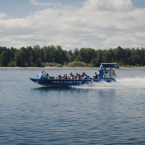 Blue speedboat with passengers on a lake under a cloudy sky.