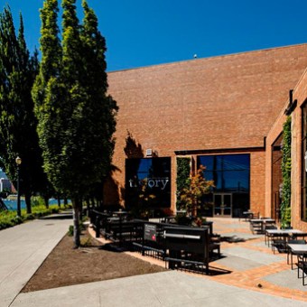 Outdoor seating area of a brick building with 'theory' on glass windows.